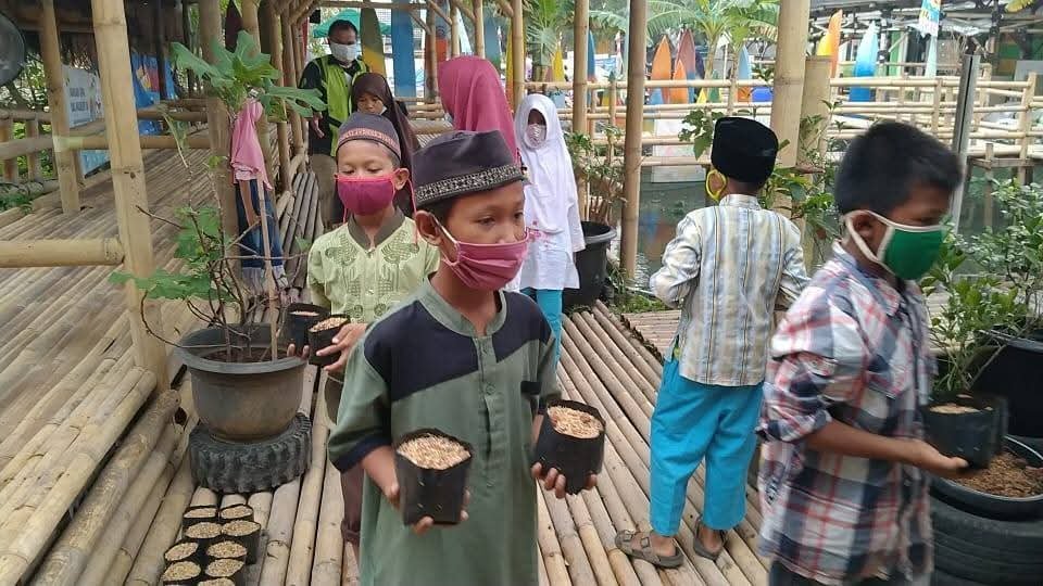 Murid membawa pot bibit di selasar bambu